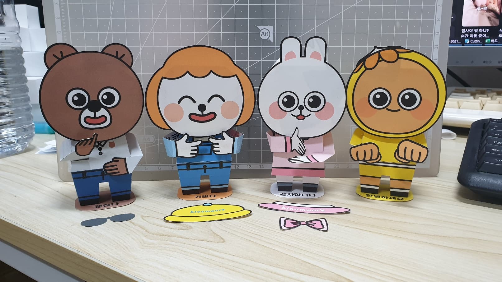 곰, 단발머리 소녀, 토끼, 노란 후드 캐릭터 넷이 괜찮다·기쁘다·감사합니다·안녕하세요 받침 위에 선 수화 페이퍼토이