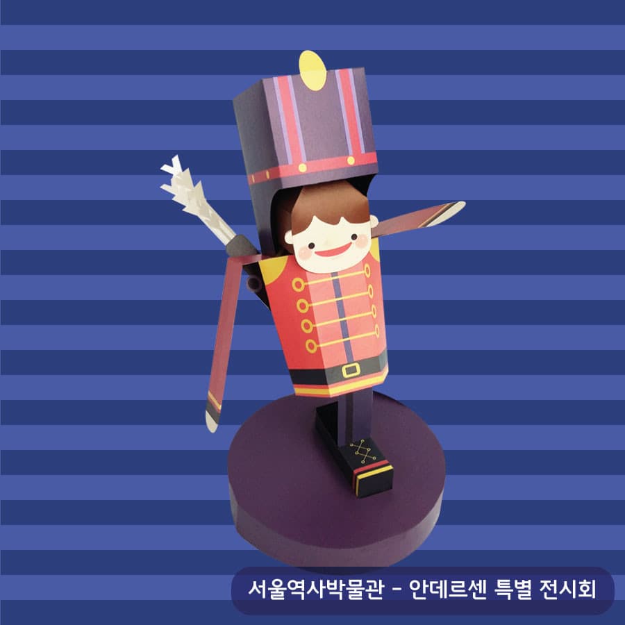 붉은 제복에 노란 단추가 줄지어 달리고 커다란 군모를 쓴 장난감 병정이 보라색 원형 받침 위에서 팔을 벌린 페이퍼토이