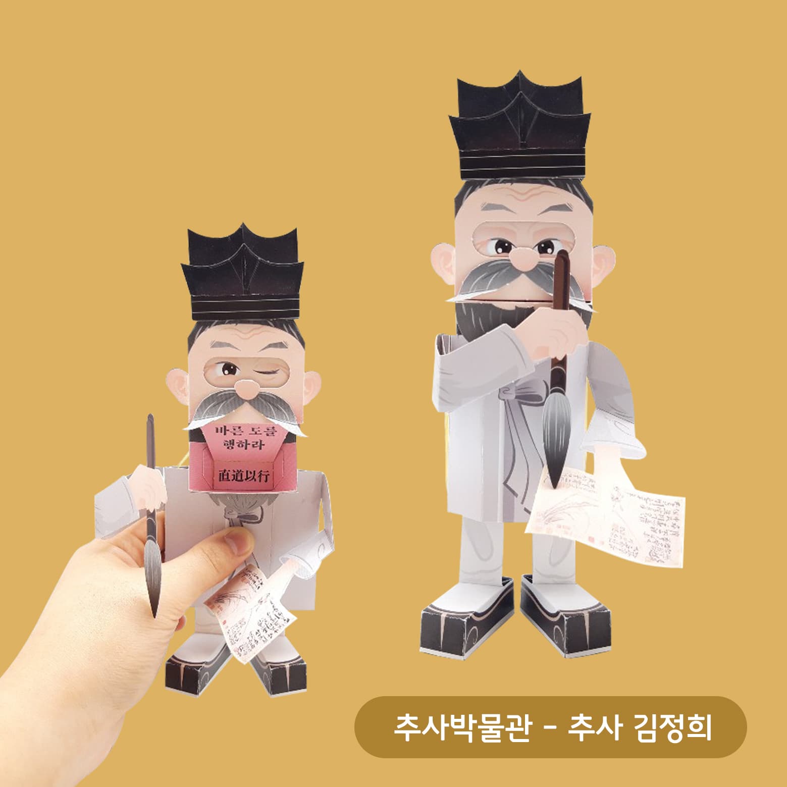 완성된 추사 김정희 종이 인형 둘, 하나는 손에 들려 가슴의 直道以行 문구판을 드러내고 다른 하나는 붓을 쥔 채 서 있어요