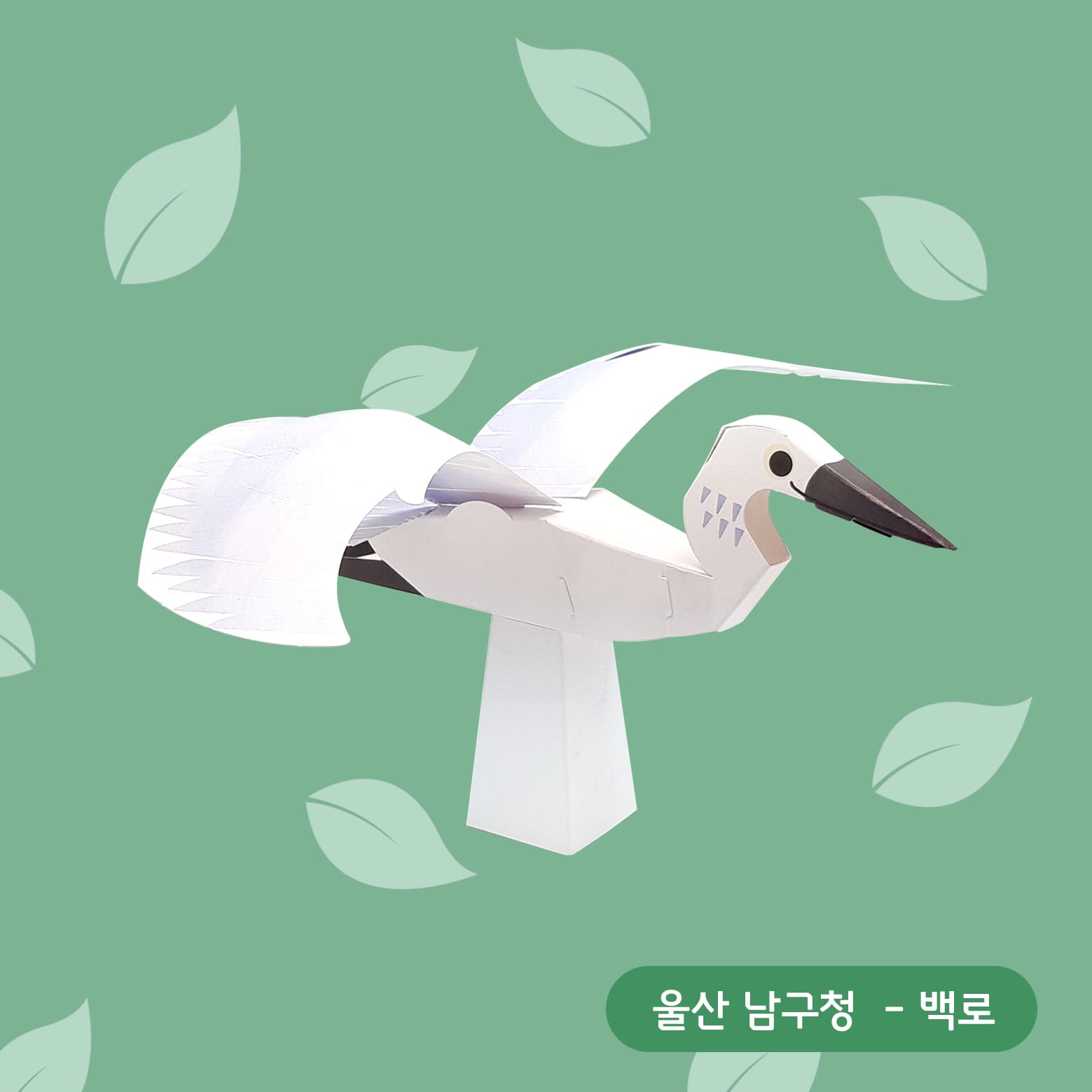 연둣빛 잎사귀 배경 위, 날개를 활짝 펴고 깃 끝을 톱니처럼 오려 낸 흰 백로 페이퍼토이가 종이 받침에 서 있다