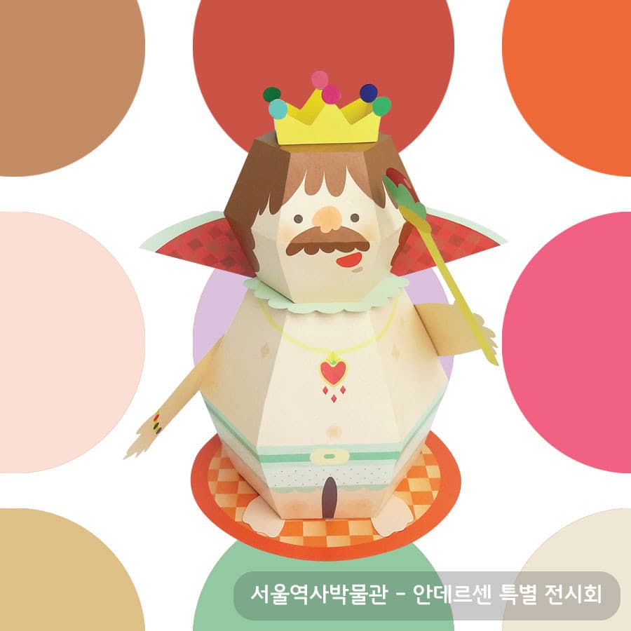 알록달록한 방울이 달린 노란 왕관에 콧수염과 붉은 체크 망토를 두른 벌거벗은 임금님이 주황 체크 깔개 위에 선 페이퍼토이