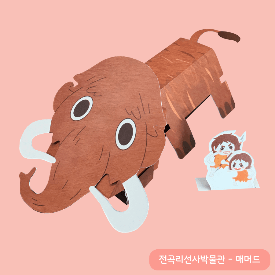 갈색 털결과 흰 상아를 살린 입체 맘모스 종이 모형, 곁에 창을 든 꼬마 원시인 남매 피규어가 서 있다